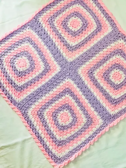 An angled view of the four-square granny blanket, highlighting the symmetry of the design. This is a timeless pattern that makes a perfect baby shower gift.