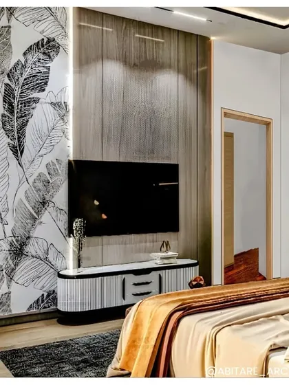 Another view of a cozy bedroom design. This angle shows the TV unit and the interplay of textures, from the wood-paneled wall to the graphic leaf-patterned wallpaper, creating a visually rich space.