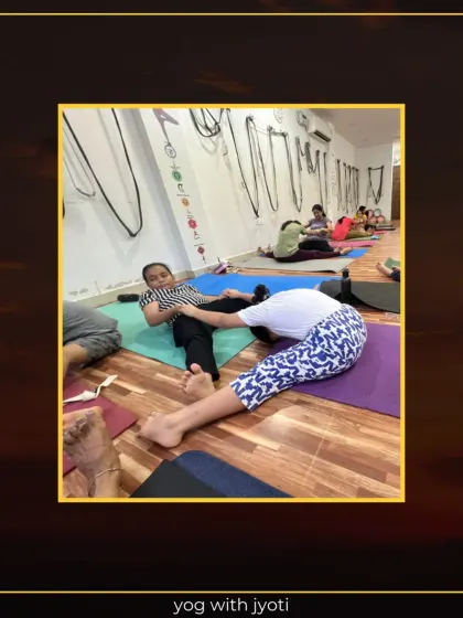 A student practices a seated forward bend with partner assistance to deepen the hamstring stretch.