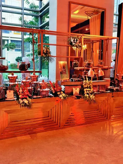 A full view of our buffet line with modern wooden counters and warm ambient lighting. This setup demonstrates our capacity to handle large-scale events while maintaining a cohesive and stylish presentation.