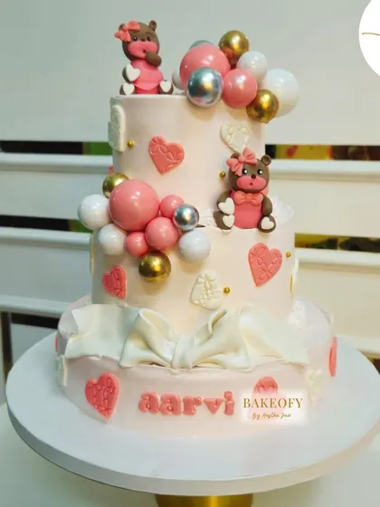A three-tier fresh fruit cake for Aarvi, decorated with cute teddy bears, hearts, and a beautiful fondant bow at the base.