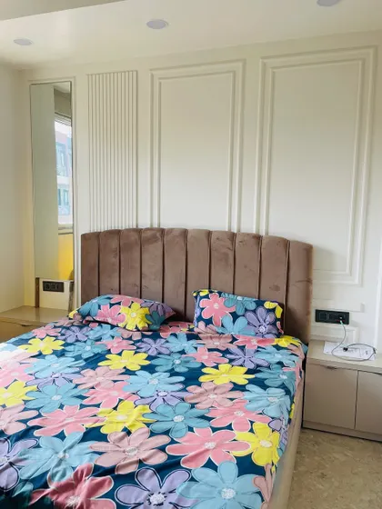 A clean and simple bedroom design. The wall features classic molding and a touch of fluted paneling, creating a subtle yet sophisticated backdrop for the bed.