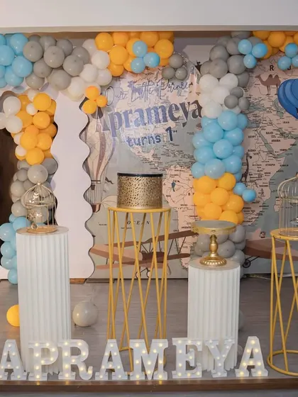 A closer look at the travel-themed birthday decor. The setup includes a world map backdrop, themed pedestals, and marquee letters spelling out the baby's name.