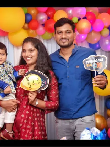 A family holds fun props while posing in front of a colorful balloon wall. We engage with families to create fun and lively portraits.