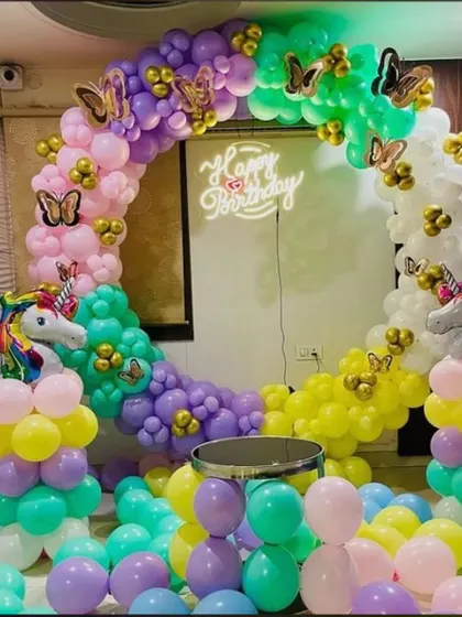 A vibrant unicorn-themed birthday party. This full-circle balloon arch uses a rainbow of colors and is accented with unicorn figures and butterfly details.