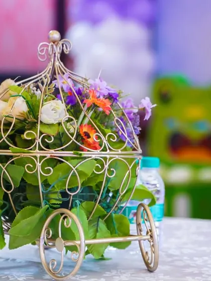 An elegant floral centerpiece in a golden carriage, a beautiful detail for a princess-themed table setting.