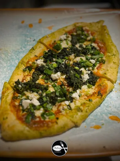 My Turkish Pide is a boat-shaped flatbread, crispy on the edges and soft inside. It's topped with a flavorful mix of herbs, cheese, and fresh greens.