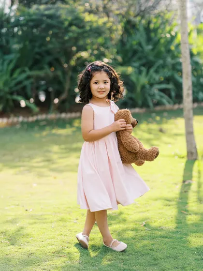 A little girl in a pink dress, holding her teddy bear. The soft, natural light makes this portrait feel so gentle and sweet.