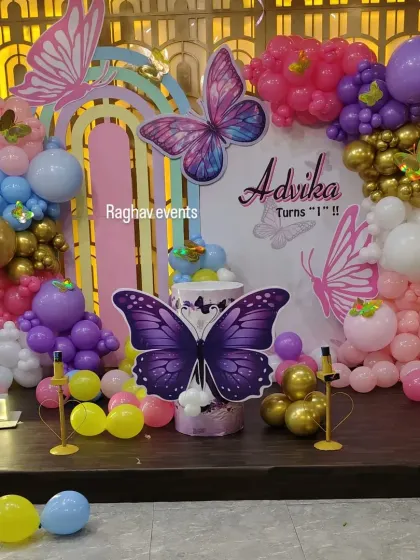 Another angle of the butterfly themed first birthday party for Advika. This view shows the intricate balloon work and the placement of the butterfly cutouts on the stage.