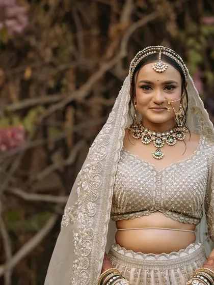 A stunning portrait of the bride in her elegant white and gold lehenga, looking serene and beautiful.