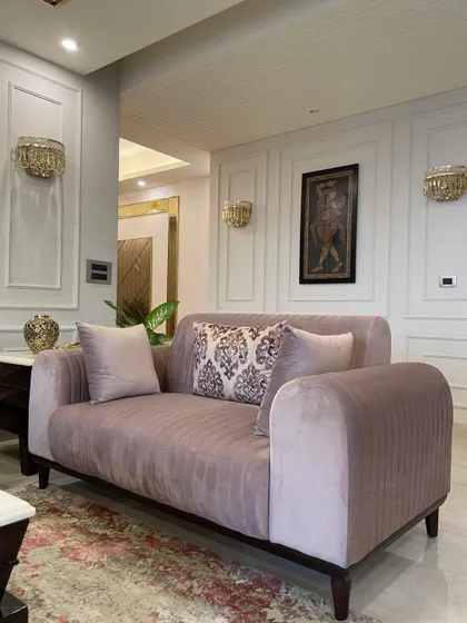 The pastel-toned living room is given a classic touch with wainscoting and elegant wall sconces. A large mirror reflects the space, making it feel larger and brighter.