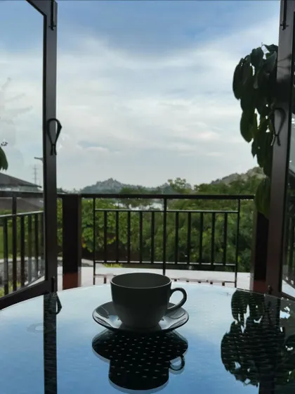 A cup of herbal tea on a balcony table overlooking the hills. This simple moment captures the essence of our retreat: finding profound peace in the quiet, mindful moments of the day.