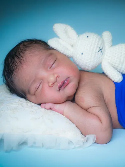 A sleepy newborn snuggled up with a tiny knitted bunny. Props like these add a touch of sweetness and scale to the photograph.
