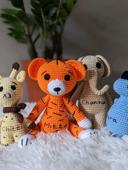 A custom set of amigurumi animals, each with their own name. This group includes Chittu the giraffe, Mittu the tiger, Chunnu the elephant, and Ira the dinosaur.