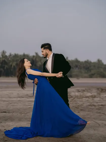 A dance on the sand. This couple looks so elegant, with her in a flowing blue gown and him in a classic black tuxedo, creating a timeless pre-wedding memory.