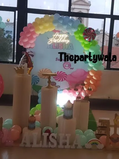 A colorful Candyland theme with a rainbow balloon arch and large candy props.