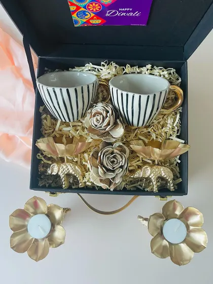 A closer look at the contents of our elegant striped ceramic cup hamper. The golden elephant t-light holders and decorative roses add a touch of luxury.