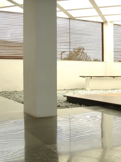 An interior zen garden with polished floors and slatted blinds at the Zanav Home Studio. This space was designed as a quiet, contemplative corner within the larger studio, bringing natural elements indoors to create a peaceful atmosphere.