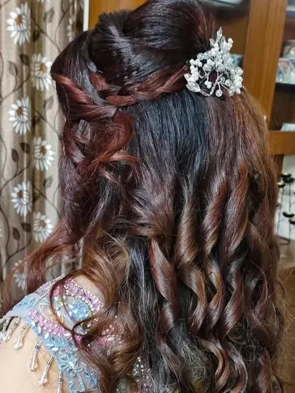 A soft and romantic half-up hairstyle with loose curls and a delicate crystal hairpiece.
