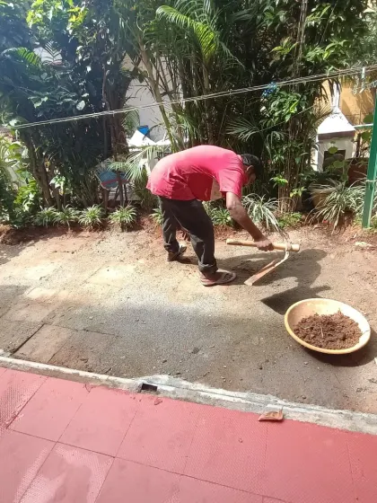 My team member is leveling the soil in a garden space, preparing it for the next stage of the installation process.