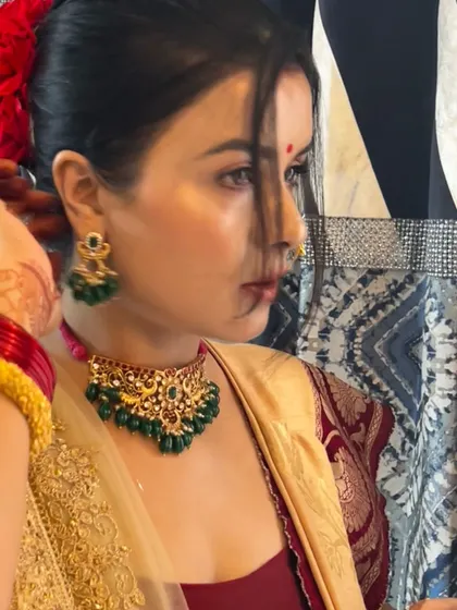 A beautiful profile shot of my client getting ready. Her hair is adorned with flowers, perfectly complementing the traditional aesthetic of the green and gold jewellery set she is wearing.