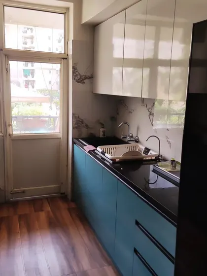 This parallel kitchen design features a striking combination of ocean blue and white laminates. The layout maximizes counter space and storage, making it ideal for compact apartments.