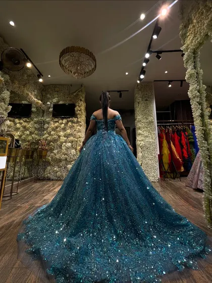 The back view of our sparkling turquoise ball gown, showing off its magnificent trail. The off-shoulder design and corset back ensure a perfect fit, while the thousands of sequins catch the light from every angle.