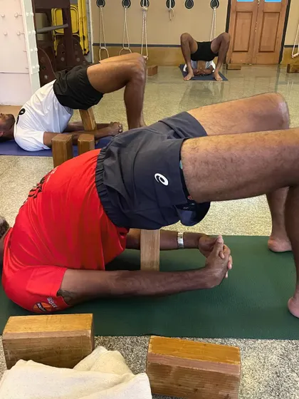 Tennis players practicing a supported Setu Bandhasana (Bridge Pose) using wooden blocks. This restorative backbend helps to open the chest and shoulders, counteracting the forward-rounding posture common in many sports.
