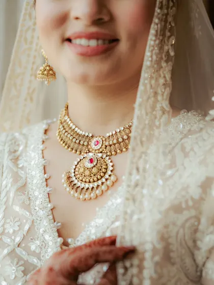 A close-up on the bride's smile and her exquisite gold necklace, capturing the joy and the fine details of her bridal look.