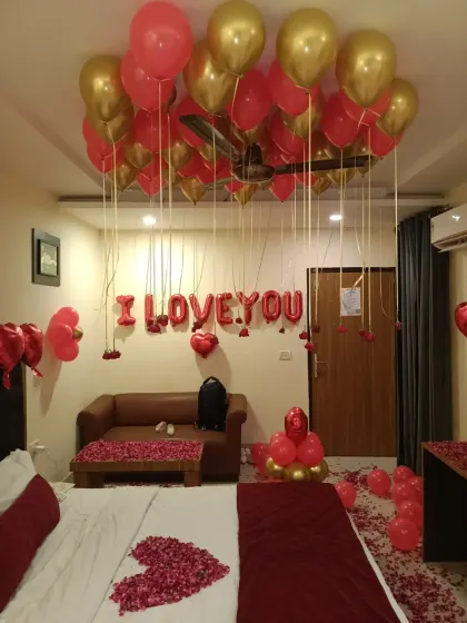 This angle of the "I love you" decor shows the foil balloon banner on the wall and the rose petals spread across the sofa, ensuring every corner of the room feels romantic.