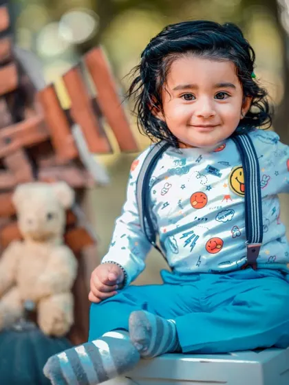 A charming portrait of a little boy with his teddy bear. The bright blue outfit and happy expression make for a heartwarming photo.