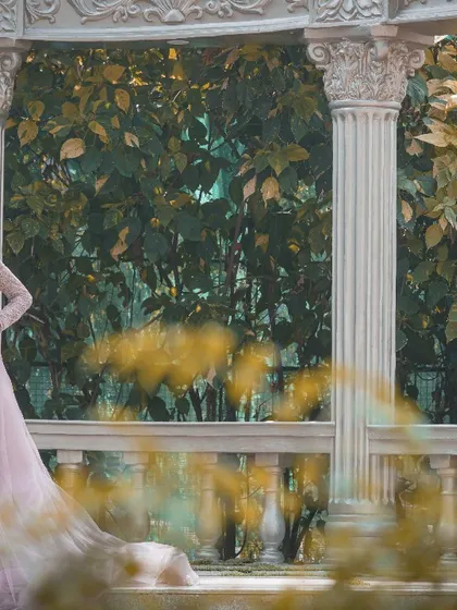 The bride-to-be looks absolutely radiant in her pink gown, framed by the elegant pillars of this garden gazebo studio set.