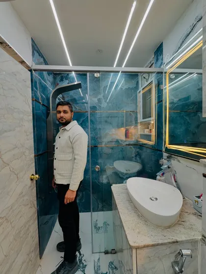 Standing proudly in a completed bathroom project. The combination of blue and white marble tiles, a glass shower enclosure, and modern lighting creates a truly luxurious feel.