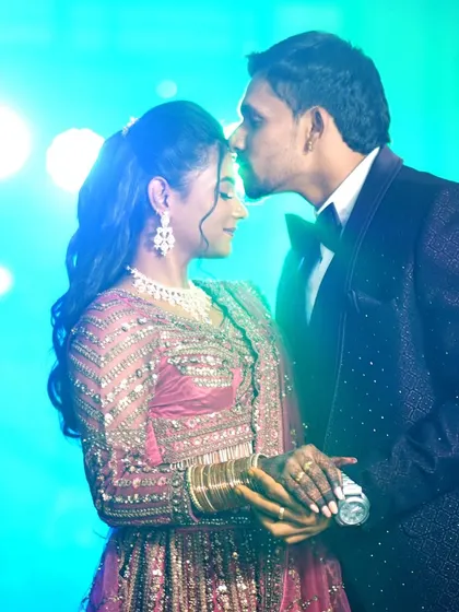 A tender moment captured under soft lighting, as the groom kisses the bride's forehead.