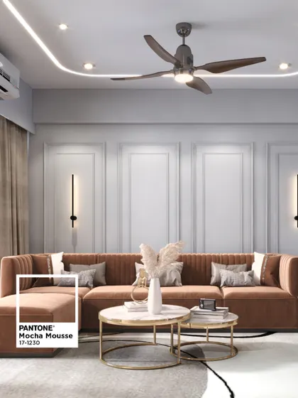 This L-shaped sofa in a warm brown hue anchors the living room, complemented by nested coffee tables and elegant wall paneling. The cove lighting adds a soft, ambient glow to the entire space.
