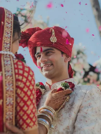 The groom's loving gaze as his bride places the garland on him during their beachside varmala ceremony. A perfect capture of love and adoration.