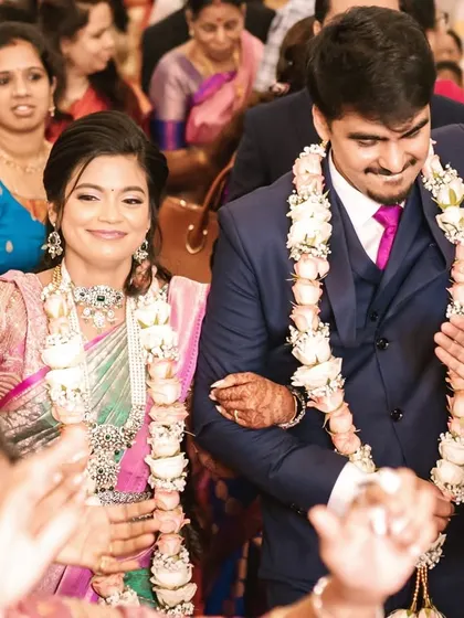 A joyful candid of the couple making their entrance. Janani's makeup is bright and festive, perfect for the celebration.