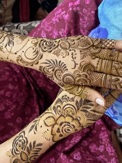 A designer mehndi with a beautiful mix of floral and leafy patterns. The design is elegant and flows beautifully on the hands.