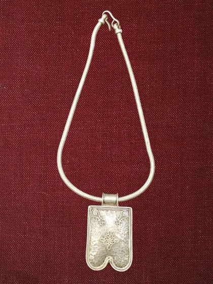 A simple yet striking oxidised silver pendant on a classic snake chain. The pendant has a unique shape and is etched with traditional motifs.