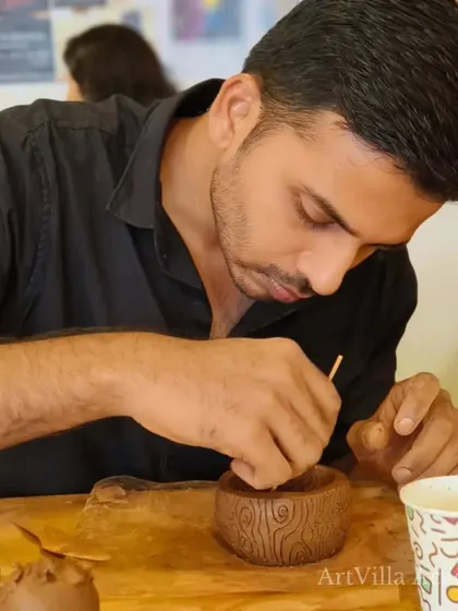 A student uses a tool to perfect the texture on his hand-built cup. The focus on detail is what elevates a simple piece into a work of art.