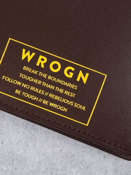 A close-up of the bold yellow branding on a dark brown 'WROGN' wallet.