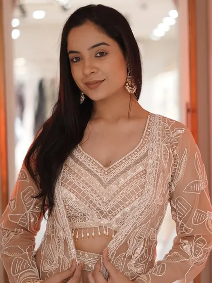 Make a statement with this breathtaking palazzo cape set. The beige pants and crop top are elevated by a beautifully embroidered longline jacket.