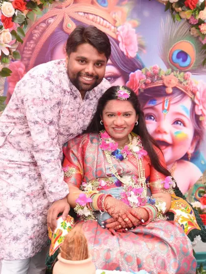 A sweet portrait of the couple during their baby shower, with a Krishna-themed backdrop adding a spiritual and colorful touch.