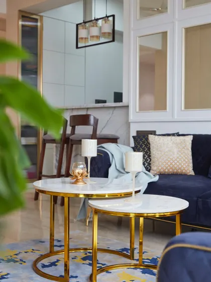 A detail shot of the nested marble-top coffee tables with gold frames, set against a vibrant blue and yellow patterned rug. This corner perfectly balances color, texture, and luxury.
