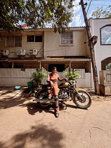 A graduate poses with her bike in a stylish outfit. Riding is an expression of personality, and she wears it well.