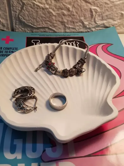 The white clam shell dish styled with a Pandora bracelet, showing how much it can hold.