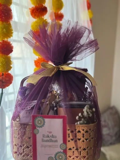 The golden Rakhi basket wrapped in rich purple tulle with a gold ribbon, ready to be gifted.
