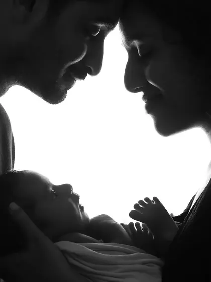 A powerful black and white silhouette showing the new family of three. This artistic photo captures the first moments of bonding between parents and their newborn baby.