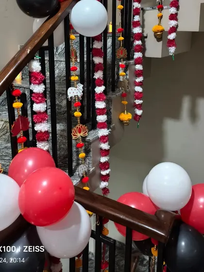 A staircase decorated for a Diwali party with balloons and traditional hanging ornaments.