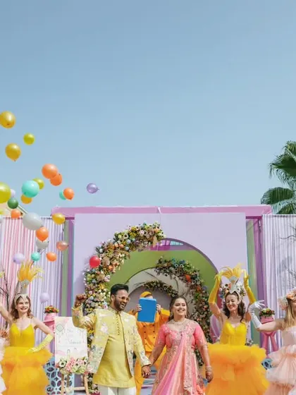 A grand, festive scene with the couple, performers, and balloons, capturing the scale of a fun pre-wedding carnival.